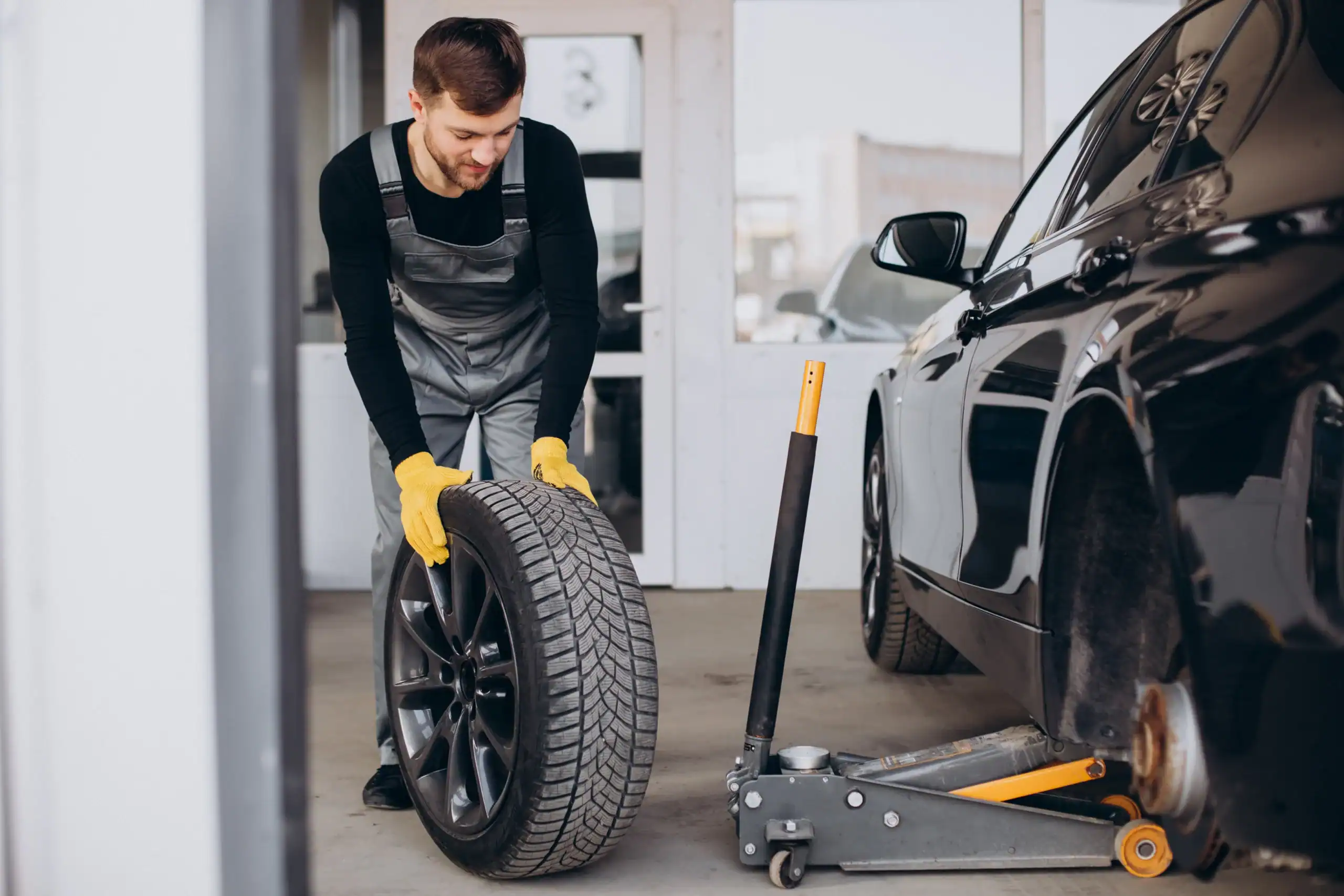 Mechanic installing a space saver spare tyre on a car